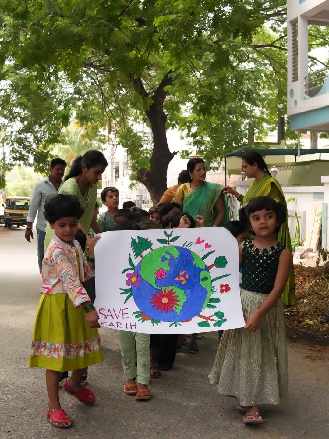 Children holding a hand-painted Save Earth poster during an awareness walk.